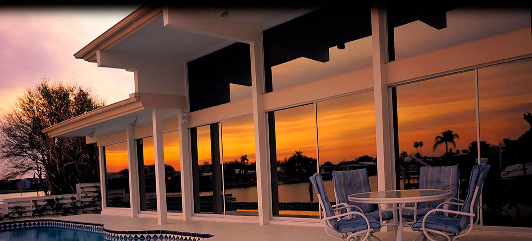 Expansive windows overlooking a pool at sunset, from JC Window Tint's gallery